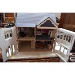 A large modern painted dolls house with four rooms and an attic room fitted with carpets and