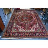 A large Persian rug with red fields and floral borders (measure!)