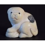 A Japanese netsuke in the form of a crouching puppy,
