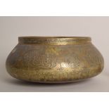 An Islamic brass bowl engraved with calligraphy and foliage