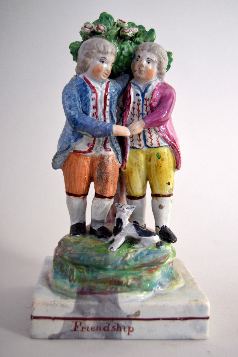 A George III pearlware 'Friendship' group by Walton of two two boys in front of a bocage a cat at