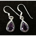 A pair of white metal teardrop earrings with pink stone