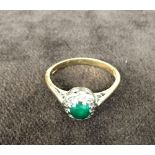 An 18ct gold ring with one mounted green stone surrounded by zirconia