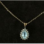 A 9ct gold chain with teardrop pale blue pendant surrounded with diamond chips