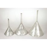 A Victorian glass funnel, wrythen moulded, 26cm; and two others, 22cm and 18cm,