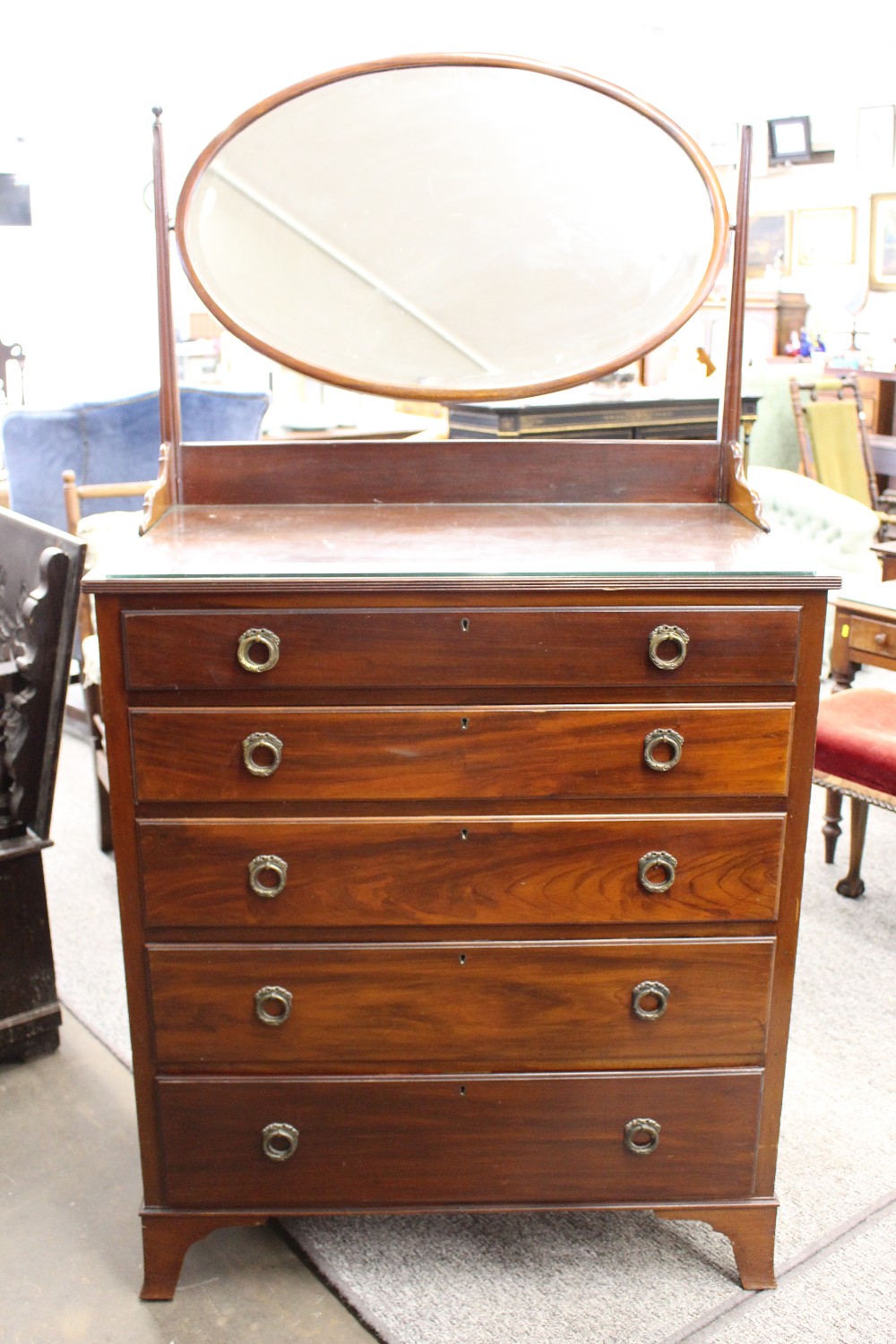 A mahogany dressing chest, oval mirror back, fitted with five graduated long drawers, bracket feet,