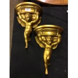 A pair of modern gilt plaster wall brackets in the form of cherubs