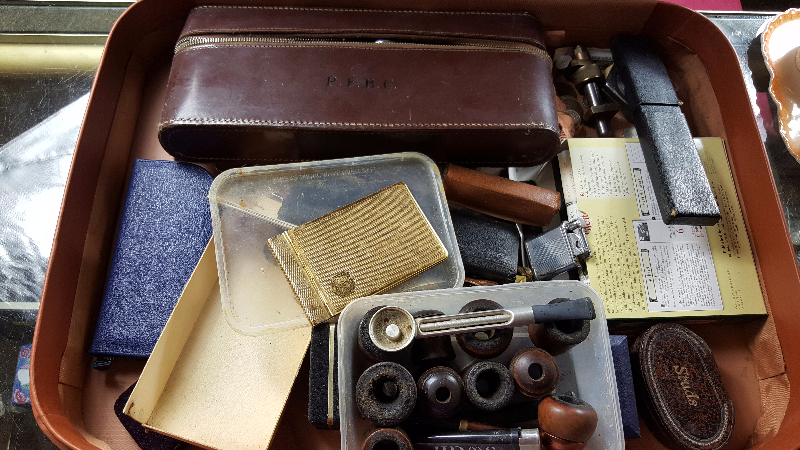 A suitcase containing lighters, cuff-links, coinage,