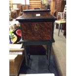 A walnut effect and ebonised cabinet on stand with lift up top