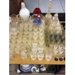 A large quantity of various drinking glasses, bowl, a ruby glass goblet, decanters and stoppers etc.