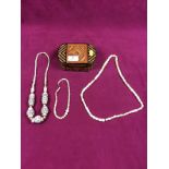 An antique oval straw workbox containing three various carved bone necklaces