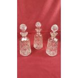 A set of three cut glass decanters and stoppers