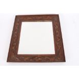 An oak Arts & Crafts seaweed carved wall mirror, 50cm x 45cm in extremes