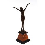 A bronzed Art Deco design figure of a semi-naked dancing girl, her arms raised aloft, raised on a