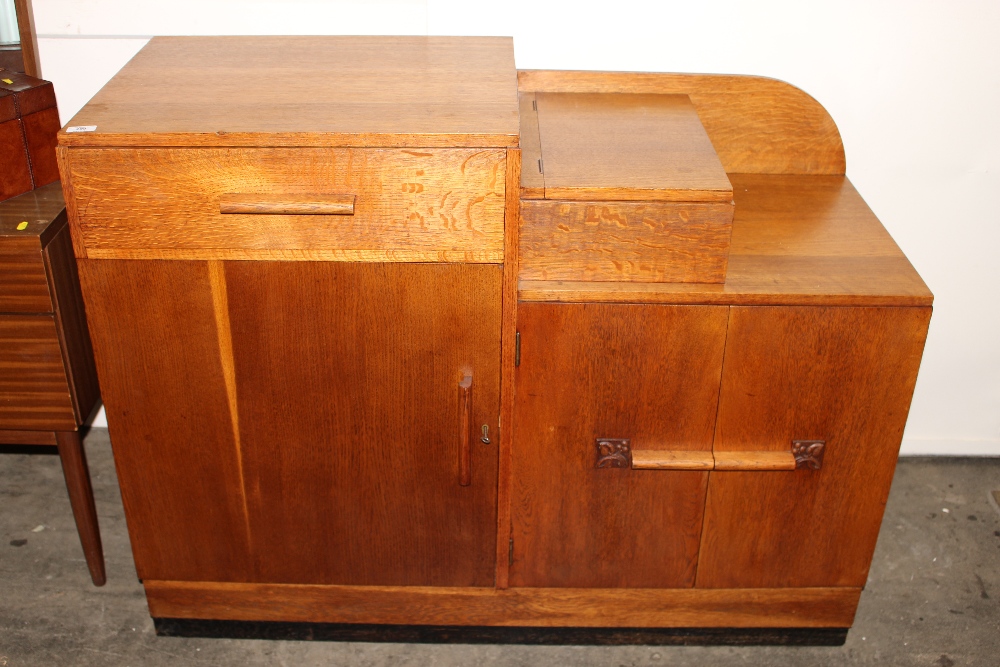 An Art Deco oak sideboard, fitted with a top lifting cutlery compartment, drawers and cupboards