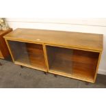 A 1960's light oak bookcase, the interior adjustable shelves enclosed by two pairs of glazed sliding