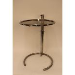 A circular glass and chrome adjustable occasional table