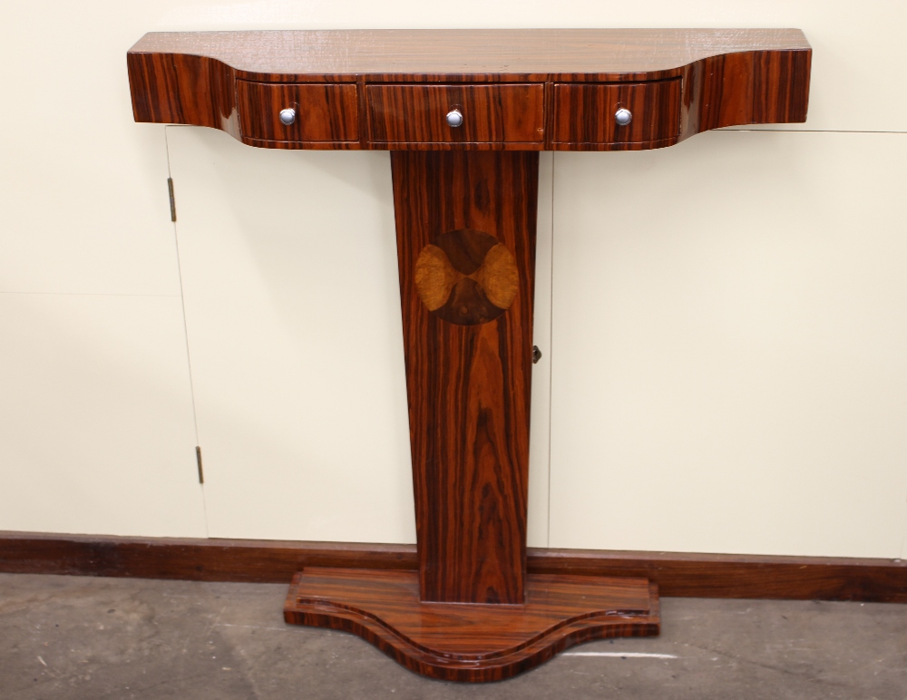 An Art Deco design three drawer serpentine fronted console table, raised on an inlaid plinth and