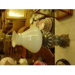 A brass and porcelain oil lamp with milk glass sha