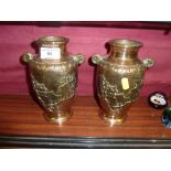 A pair of bell metal twin handled vases decorated