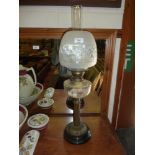 A brass oil lamp with clear glass reservoir