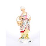 A 19th Century German porcelain figure, depicting a girl carrying a basket with brightly coloured