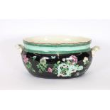 A late Victorian famille rose decorated china foot bath, flanked by foliate handles heightened in