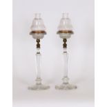 A pair of cut glass candle lamps, having gilt metal mounts and oval star cut bases, the moulded drip