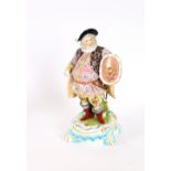 A 19th Century German porcelain figure of Falstaff, in brightly coloured attire, reclining against a