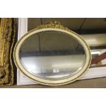 An oval and bevel edged wall mirror with ribbon ti