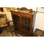 An oak and leaded glazed display cabinet raised on