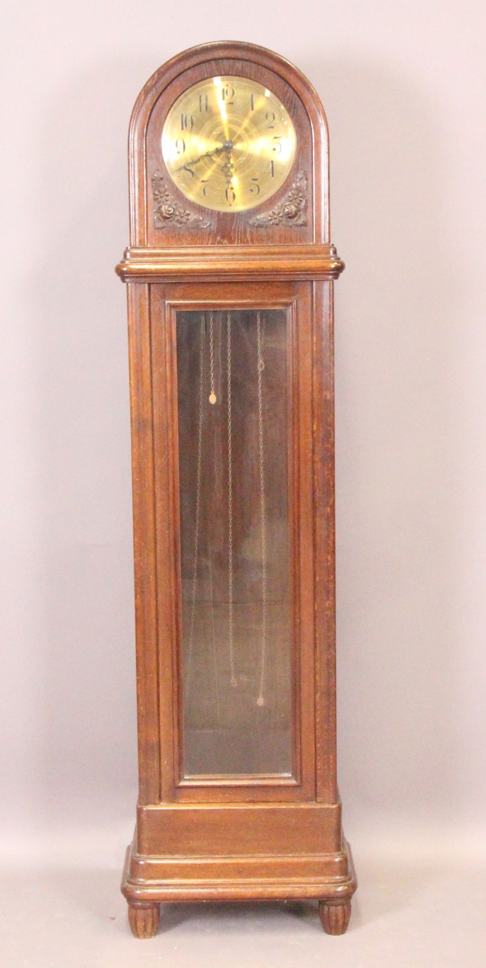 An oak cased longcase clock with arched top over a fully glazed door,