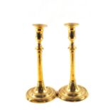 A pair of late 18th Century Brass candlesticks with cylindrical and knopped stems and circular