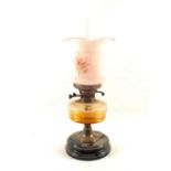 An oil lamp with pink glass shade