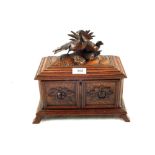 A Black Forest two compartment tea caddy with floral carving and twin bird finial