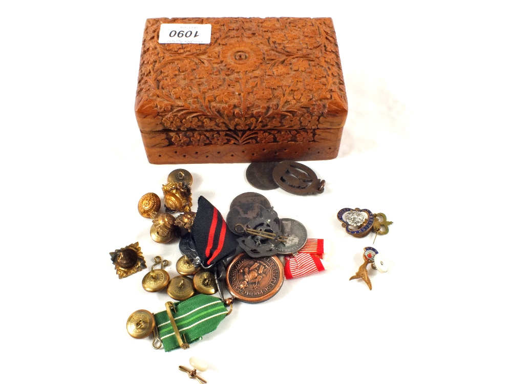 A collection of badges and buttons in carved wooden box