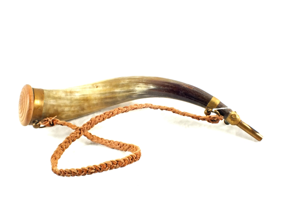 A large powder horn with wooden end and sprung charger