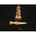 A vintage Japanese Ivory carving of a man holding a bird aloft a bone paper knife and a magnifying