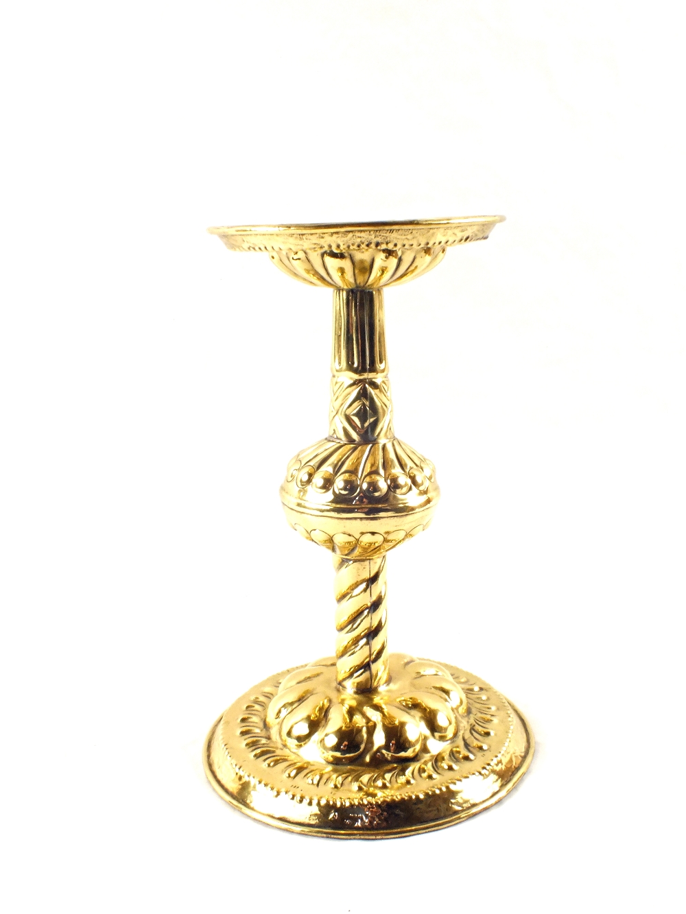 A Scandinavian Arts and Crafts Brass candle stand with repousse decoration and wide circular base,