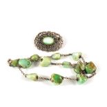 A white metal and green stone set brooch with a white metal green stone necklace