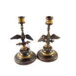 A pair of Brass and patinated Bronze candlesticks with eagle stems and rising circular bases having