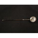 An unmarked toddy ladle with horn twist handle set with 1709 Queen Anne shilling