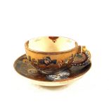 A 19th Century Japanese cup and saucer with grin faced immortal decoration by Choshuzan