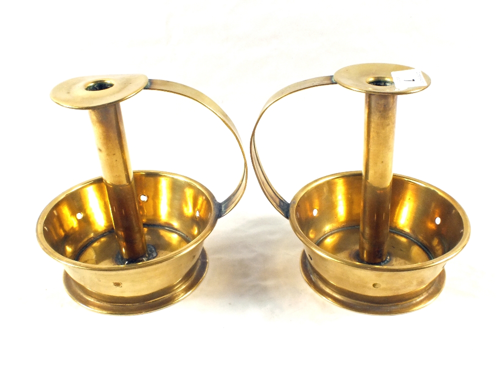 A pair of Arts and Crafts Brass chambersticks with deep dished circular bases having pierced