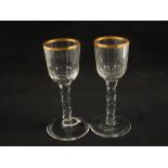 A pair of Georgian wine glasses with gilt rimmed cut bowls on faceted stems on plain feet,