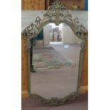 A wall mirror in shaped Brass surround,