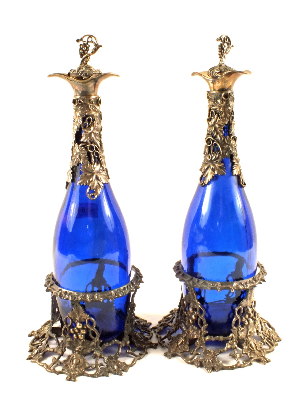 A pair of Victorian blue glass decanters with vine leaf mounts, stoppers and stands,