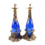 A pair of Victorian blue glass decanters with vine leaf mounts, stoppers and stands,