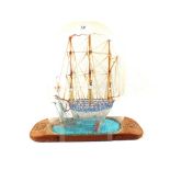 A multi coloured glass Frigger under dome on wooden base with ships wheel carving,