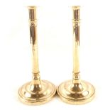 A pair of late 18th Century Brass candlesticks with cylindrical columns and wide circular bases,